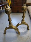 A pair of brass fire dogs with engraved decoration and bulbous reeded tops.