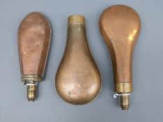 Three copper and brass powder flasks, two with bevelled edges, largest 21cm long.