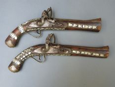 A pair of mother of pearl inlaid flintlock hammer action pistols with locks stamped 1875 and 8.