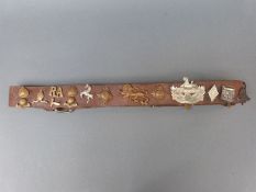 A collection of mainly military badges and collar badges on belt including Gloucestershire Regiment