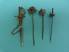 Three white metal filigree stick pins, one in the form of a horseshoe, jockey cap and crop,