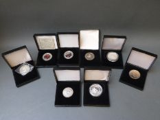 Eight cased crown sized coins including silver and nickel silver examples,
