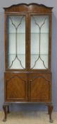 An early 20thC walnut glazed display cabinet with cupboard below, raised on cabriole legs,
