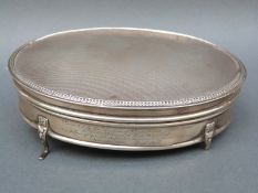 A George V hallmarked silver oval dressing table pot with engine turned lid and gilt interior to