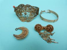 A gilt filigree bangle with scrolling and floral design, a yellow metal bangle,