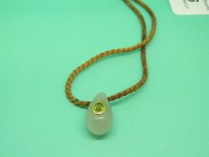 A jadeite pendant in the shape of a pear set with an oval peridot with a gold surround on a plaited