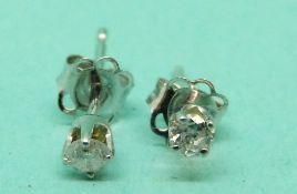 A pair of 14ct white gold earrings each set with a diamond.