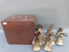 A cased set of eight bronze hand bells with leather straps embossed with their note