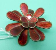 A silver brooch set with red enamel in the form of a tiered flower,