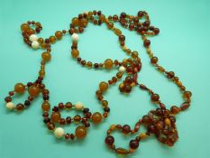 An amber necklace made up of faceted translucent beads and ivory beads and another amber necklace