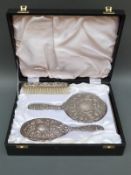 A modern cased hallmarked silver mounted dressing table set comprising mirror and two brushes,