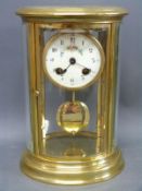 A brass cased mantel clock with four bevelled and curved glass panels,
