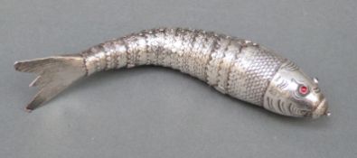 A white metal articulated novelty fish with engraved scales and red cabochon eyes,
