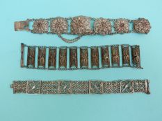A white metal filigree bracelet made up of six layered flowers and two other filigree bracelets
