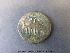 An ancient bronze coin from Pakistan depicting a standing Moghul obverse and an ox with a standing