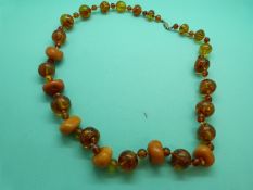 An amber necklace made up of irregular butterscotch colour beads alternated with translucent
