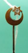 A yellow metal stick pin marked 15ct gold in the form of a crescent and star set with an old cut