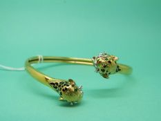 A 14ct gold bangle in the form of two leopards set with emerald eyes,