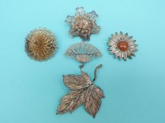 A white metal gilt layered flower brooch and four white metal filigree brooches in the form of