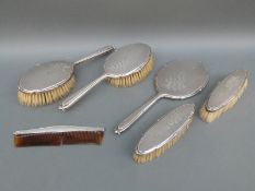 A modern hallmarked silver dressing table set comprising hand mirror, four brushes and comb,