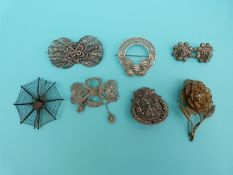 Five white metal filigree brooches, one with gilt decoration in the form of flowers and bows,