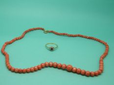 A coral necklace with a 9ct gold clasp and an 18ct gold ring set with a sapphire surrounded by