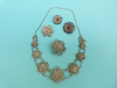A white metal filigree necklace made up of layered floral links,