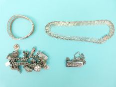 A silver charm bracelet with 20 charms, a silver ingot,