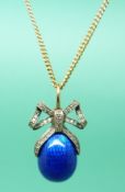 A 14ct gold pendant with a blue guilloche enamel egg and clear stones set in a bow shape.