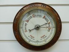 A circular aneroid barometer in cased oak mount,