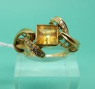 An 18ct gold ring set with a square step cut citrine and diamonds in a twist setting (Size R)