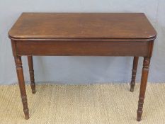 A Georgian mahogany fold over card or occasional table raised on turned legs,