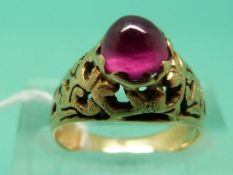 A yellow metal ring set with a ruby cabochon with pierced shoulders (Size I)