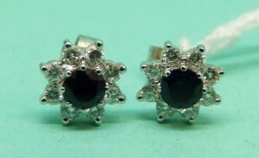 An pair of 18ct white gold earrings each set with a sapphire surrounded by diamonds.