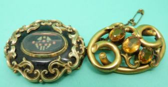 A Victorian brooch with a glass section to the centre and scrolling decoration and another