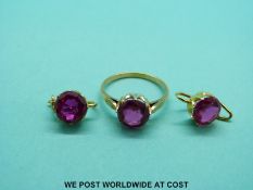 A yellow metal ring set with a round cut synthetic ruby with matching earrings.