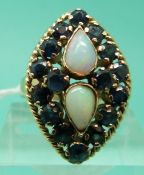 An 18ct gold ring set with two teardrop shaped opal cabochons and sapphires in a marquise shaped