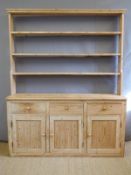 A pine dresser with three drawers over three cupboards and plate rack above,