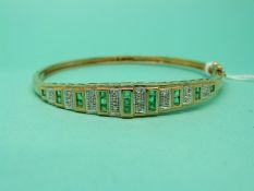A 9ct gold bangle set with emeralds and diamonds