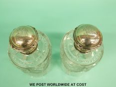 A pair of Fabergé silver topped cut glass scent bottles with ribbon decoration,