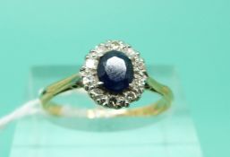 An 18ct gold ring set with an oval sapphire surrounded by diamonds (Size M)