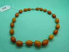 A graduated amber necklace made up of egg yolk coloured oval beads on original knotted string, 47g.