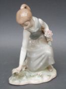 A Lladro figurine of a girl picking flowers