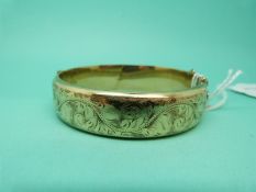 A hallmarked 9ct gold bangle with chased floral decoration,