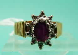 An 18ct gold ring set with an oval ruby surrounded by diamonds (Size O)