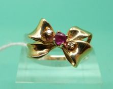 A 14ct gold ring set with a ruby and diamonds in a bow shape (Size L)