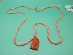A coral necklace with a yellow metal pendant in the form of a Buddha