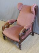 A Victorian mahogany wing back chair with scrolling pierced arms,