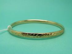 A 9ct gold bangle with floral decoration, weight 5.