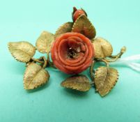 A gilt brooch set with a coral rose